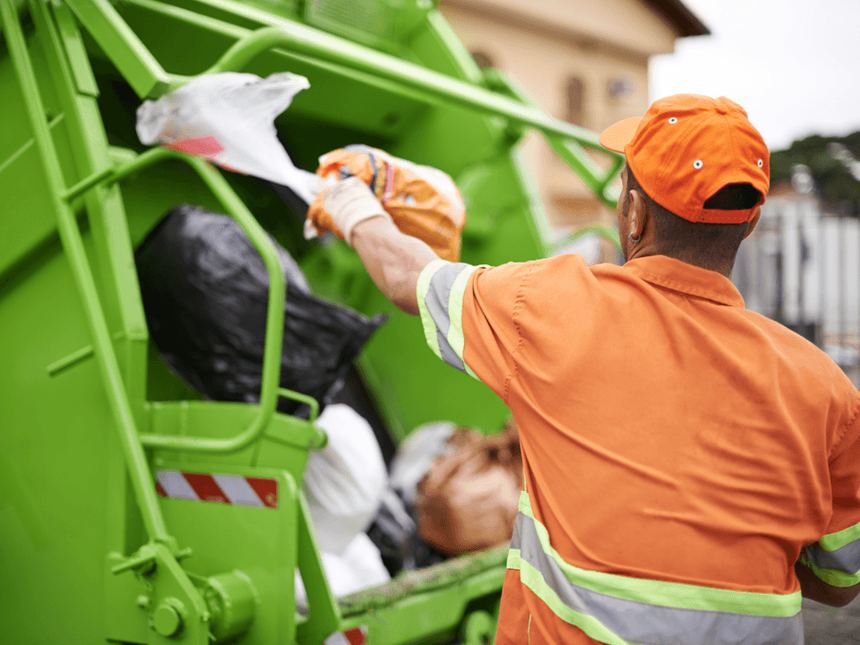 Operador de E-Colect cargando residuo al camión compactador.